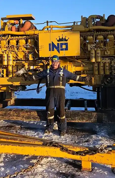 Independent Rebuild Specialist field technician standing beside a remanufactured CAT engine during on-site support in winter conditions.