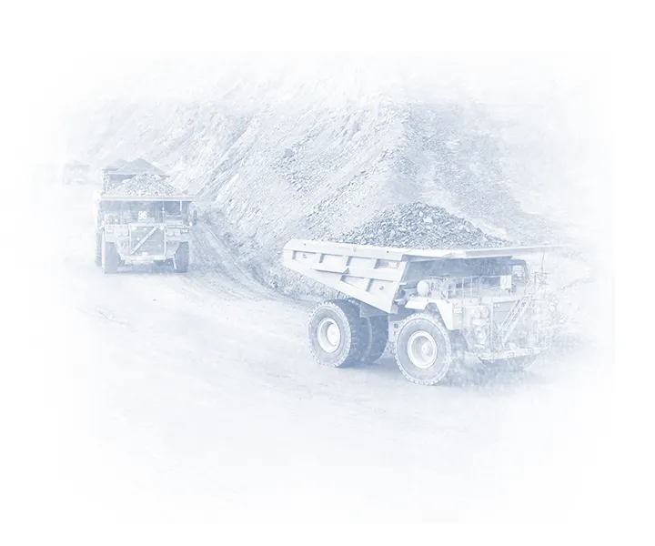 CAT mining haul trucks carrying material along a haul road in an open-pit mine.