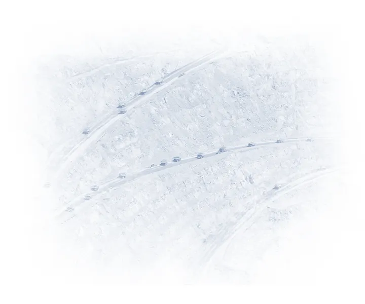 Aerial view of an open-pit mine with multiple CAT mining haul trucks traveling along terraced haul roads.
