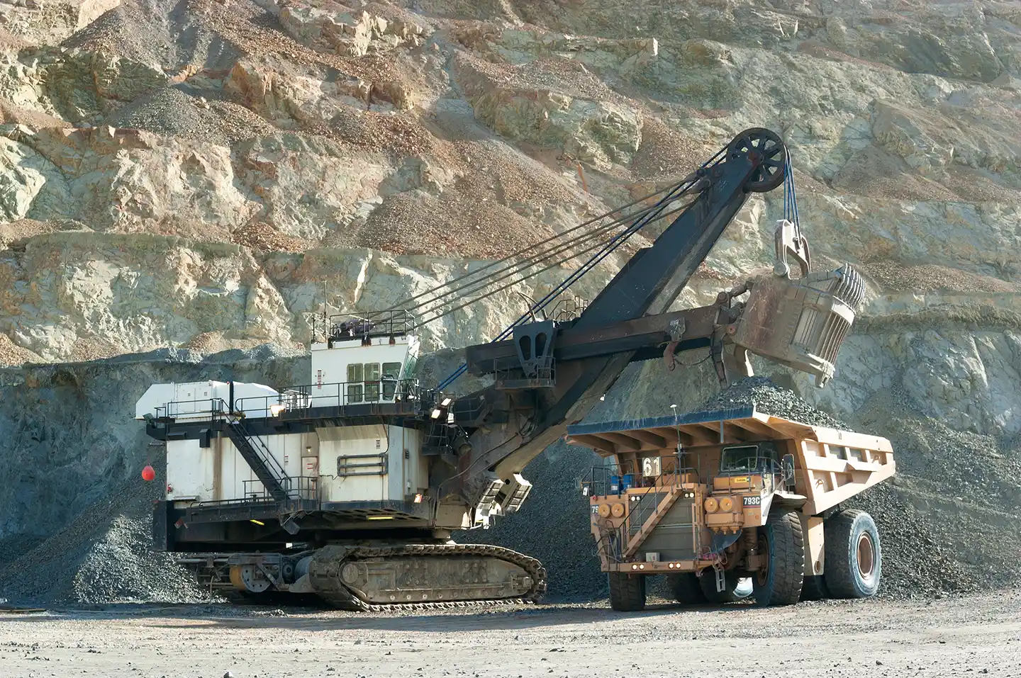 CAT 793C mining haul truck being loaded by a large mining shovel in an open-pit mine.
